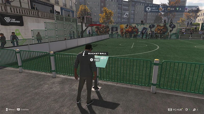Player stands next to the Bucket Ball info board overlooking a football pitch.