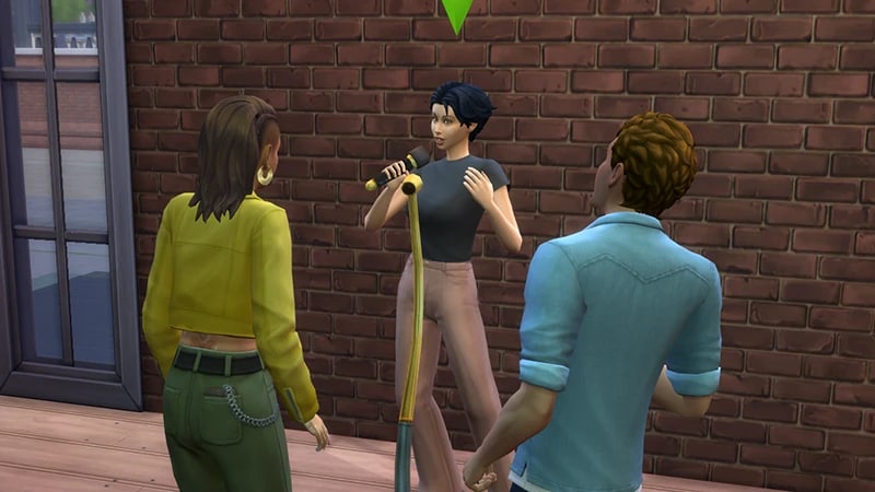 Sim com cabelos pretos e escuros atrás de um microfone amarelo, fazendo uma apresentação stand-up para uma plateia de Sims.