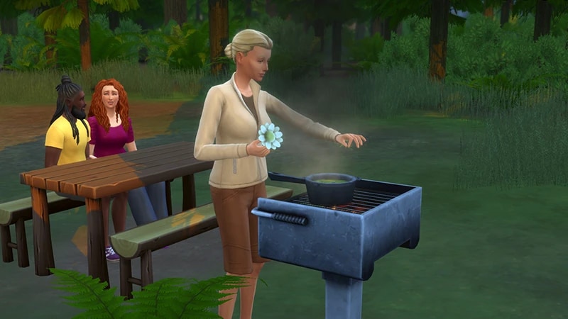 A blonde Sim stands at a grill, about to add a white flower to a pot. Behind her, two Sims sit at a picnic bench.