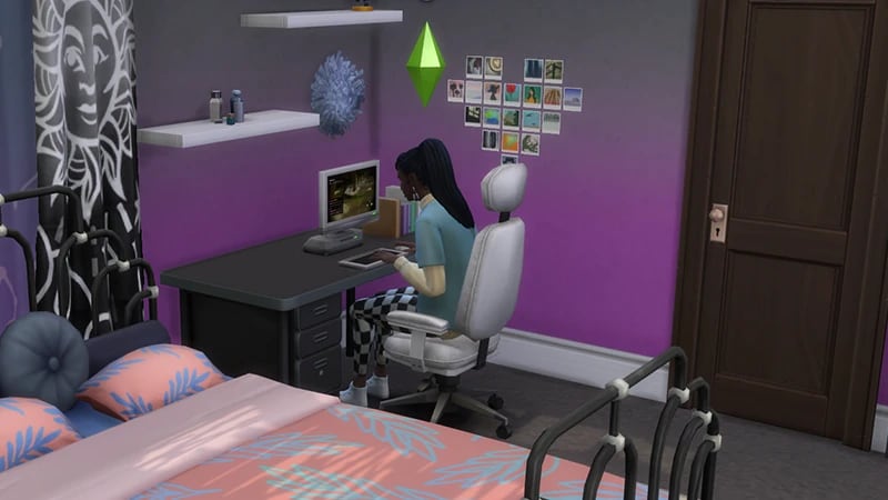 A Sim with black hair sits on a white chair at a desk playing video games.