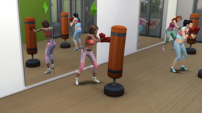 A brown haired Sim stands in front of a full length mirror at a gym punching a red and black boxing bag.
