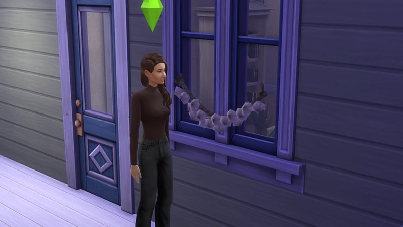 A Sim wearing all black stands in front of a house where the window is wreathed in garlic to ward off Vampires.