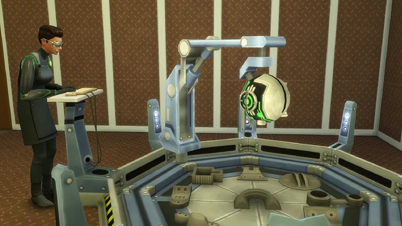 A Sim wearing goggles uses a keyboard and mouse to one side of the Invention Constructor machine in The Sims 4.